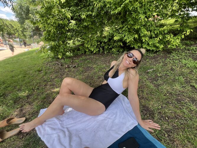 Woman in a black and white swimsuit sitting on a towel in a park